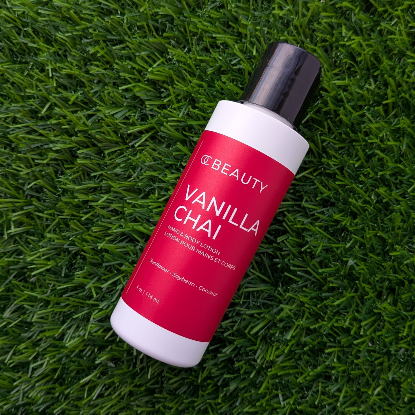 A bottle of OC BEAUTY Vanilla Chai hair colour resting diagonally on a textured green grass background.