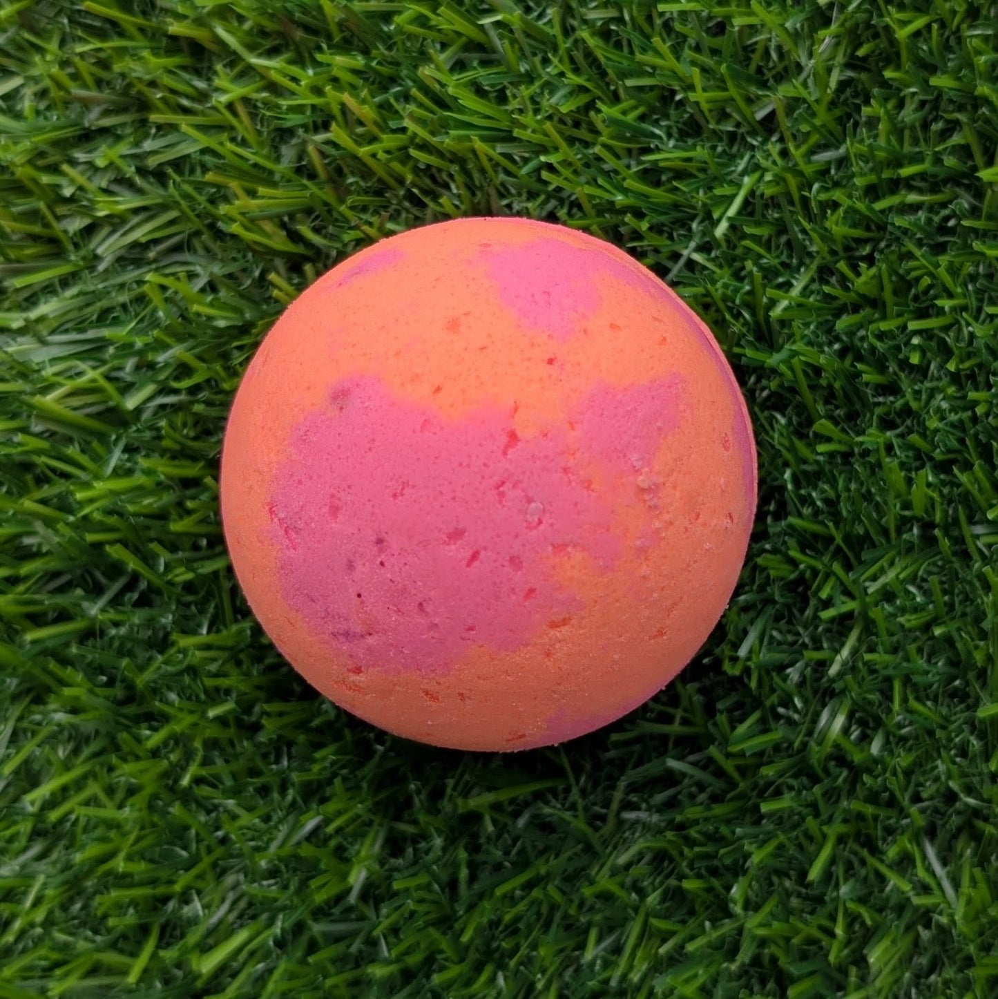 Pink and orange bath bomb on green grass