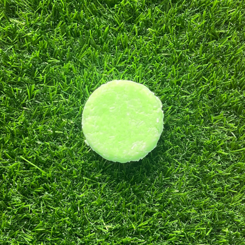 a green Tea Tree + Peppermint Shampoo Bar On gras
