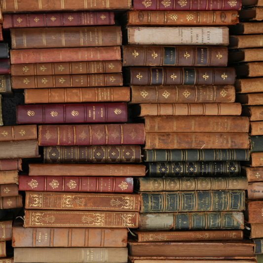 Stack of old, leather-bound books with gold embossing.