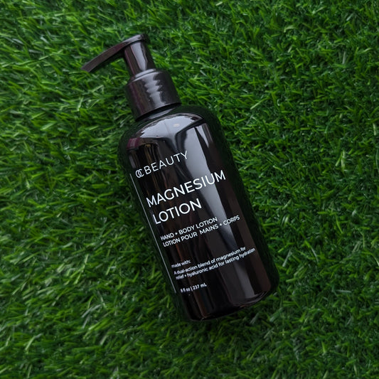 Black bottle of magnesium lotion on green grass