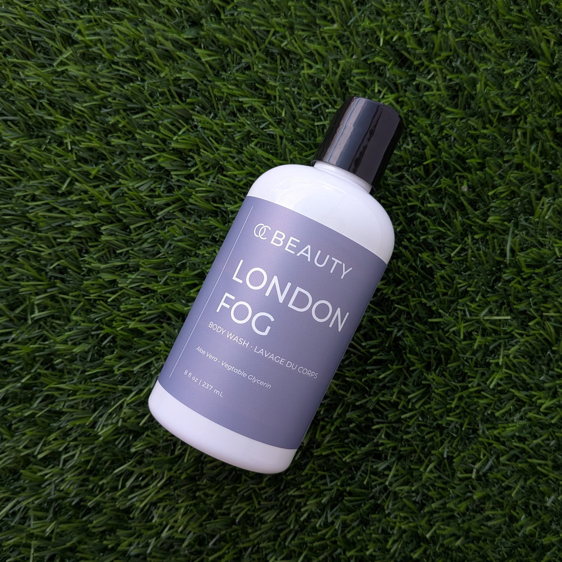 A bottle of London Fog body mist by Beauty of Joseon lies diagonally on a textured green artificial grass surface.