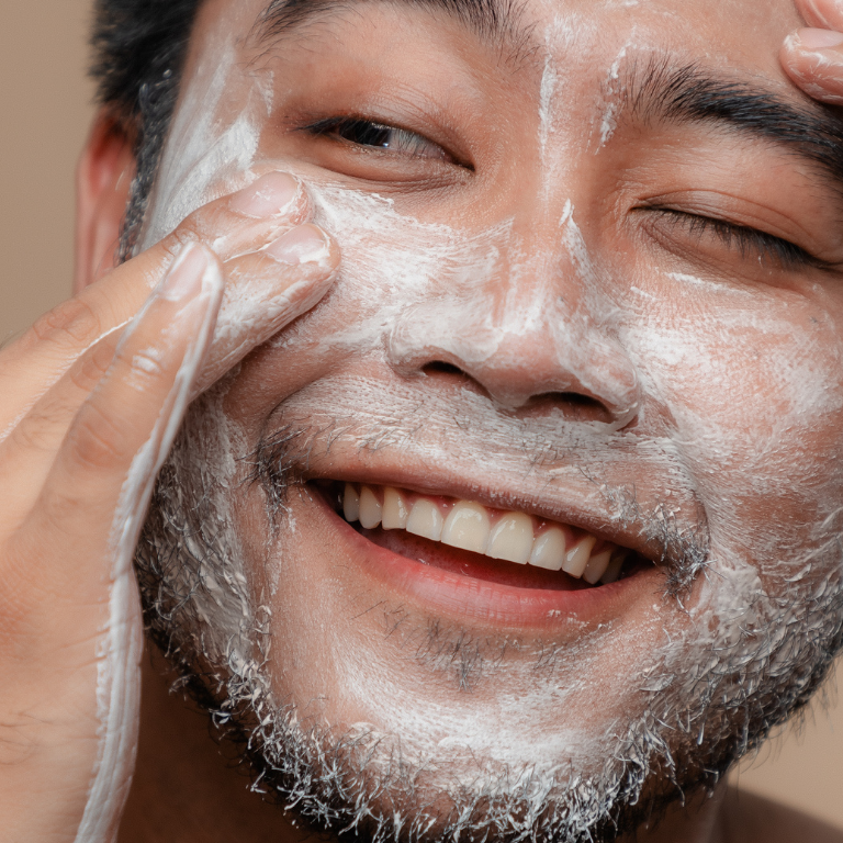 Man applying a facial mask with a neutral background